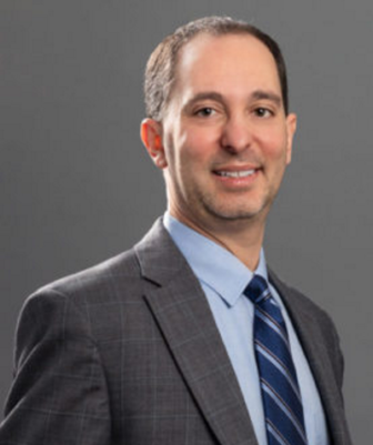 nonprofit strategy: headshot of a man with lght brown hair wearing grey suit, blue shrt abs striped blue tie smiling into the camera