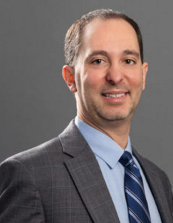 nonprofit strategy: headshot of a man with lght brown hair wearing grey suit, blue shrt abs striped blue tie smiling into the camera