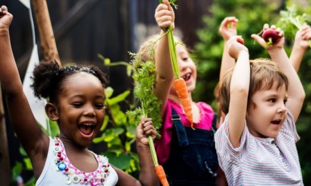 State of childhood obesity report cover: group of happy children in garden holding freshly picked carrots