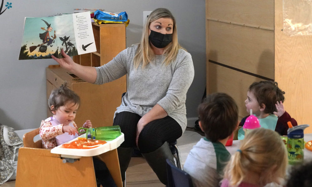 pandemic child care crisis hampers economy: woman reading to small children with mask on