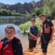 Summer hiking: group of 3 youths on outdoor lake trail adventure