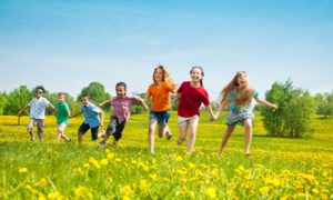North and South Carolina child welfare, child wellbeing and family grants: group of young children running in field of yellow flowers