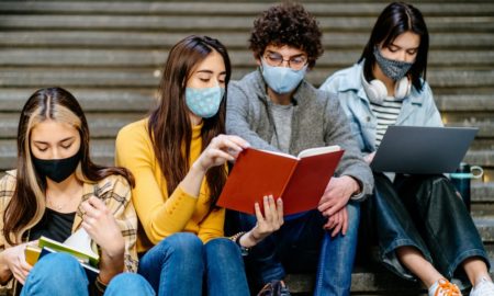 youth-led Hispanic/Latin community COVID grants: group of Latin students studying on steps in facemasks