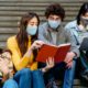 youth-led Hispanic/Latin community COVID grants: group of Latin students studying on steps in facemasks