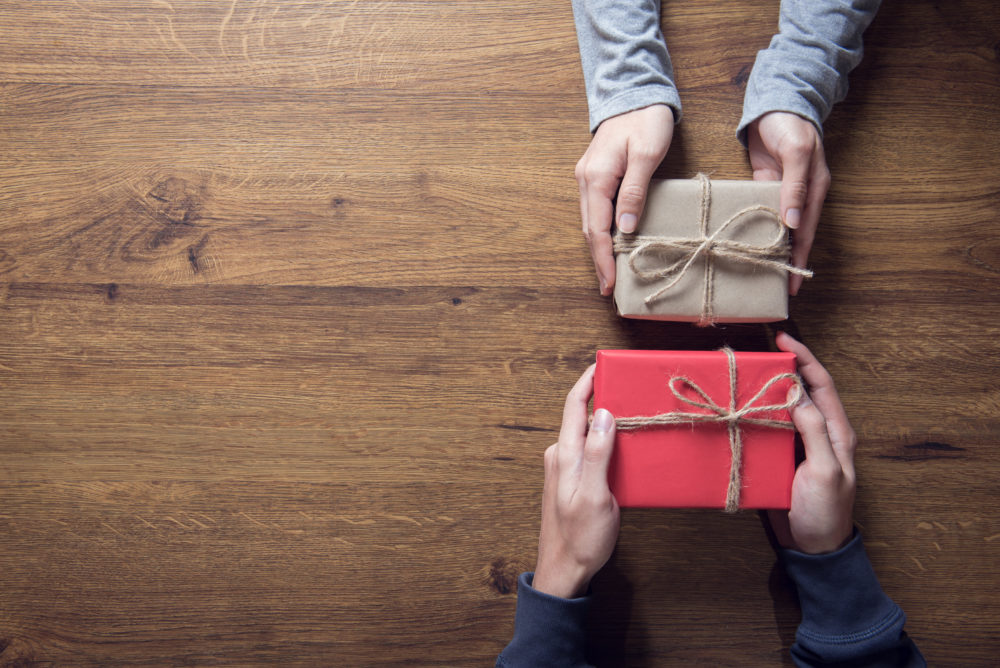 Improving year-end giving tips: hands holding gifts to give on wooden table