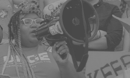 women and girls of color organization grants: black woman with megaphone at rally