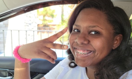 Special ed diagnosis problems: teen black girl showing peace in car seat