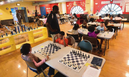 BOOST: Several young students sit at tables in colorful classroom playing chess