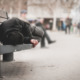 NY Homeless Payments: Person in dark clothes sits cross-legged on city bench huddled over