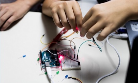 optics and photonics STEM education grants: hands working on electronic STEM project