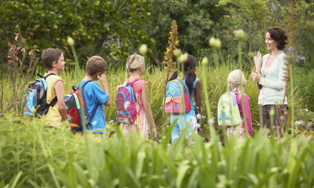 out-of-school time, outdoor learning , OST workforce: teacher and students in backpacks out in nature