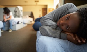 youth service grants: young, black girl laying on shelter bed looking sad