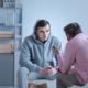 youth mentoring, child/youth mental health: teenage boy in hoodie talks to psychologist