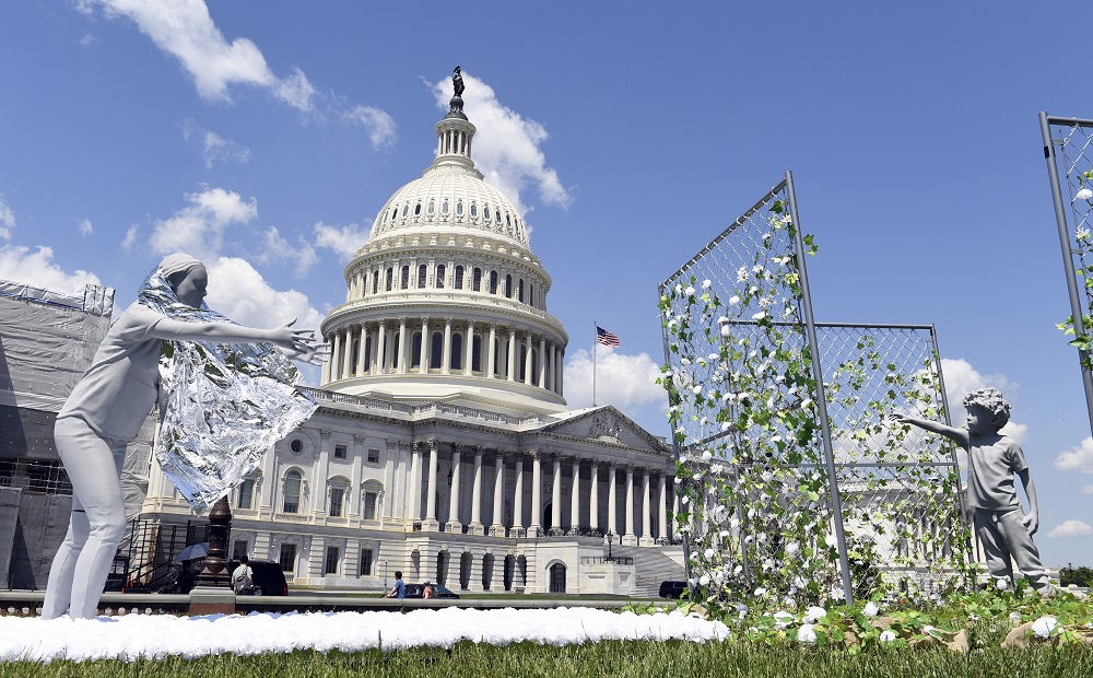 families separated at border now fear extortion: art installation with white flowers outside Capitol on clear day