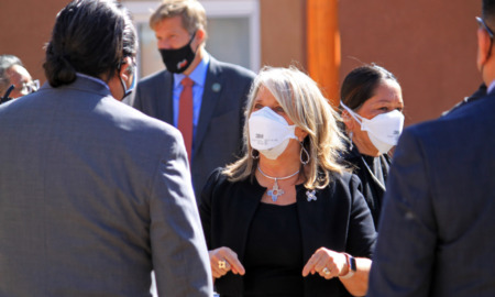 New Mexico Educaton Plan: Group of adults in business attire wearing masks stand ina group talking to each other