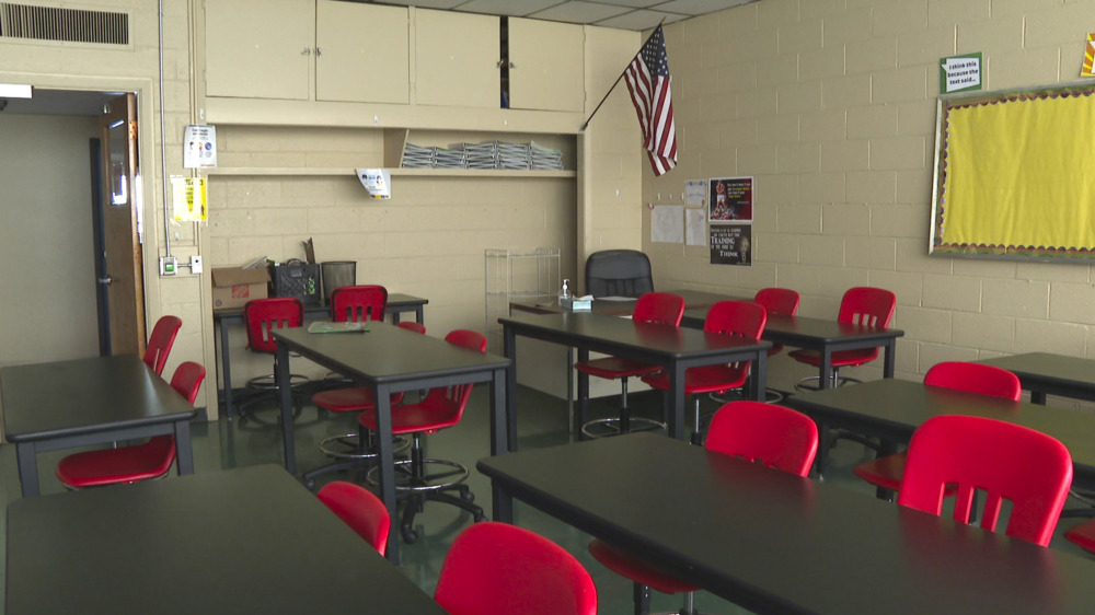 Remote Learning: Classroom with no students and several rows of brown desks with red chairs.