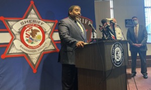 social worker safety concerns after killing: black man in suit at podium giving press conference in front of Sheriff logo