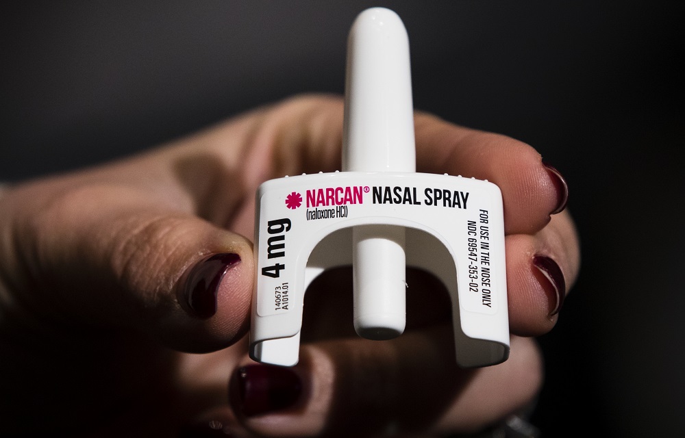 youth overdose renews pleas for Narcan in schools: hand holding Narcan nasal spray on black background