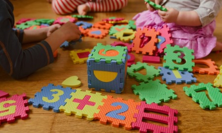 childcare grants: children playing with educational puzzle toys on floor