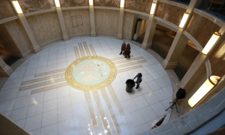 Juvenile justice sentencing: Interior of round 3-story room with tan plastered walls and a white tiled floor with a circle and four horizontal and vertical lines in gold tiles