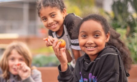 Los Angeles region education, health, homelessness, social justice grants: three smiling kids holding freshly picked food