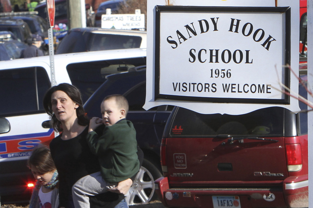 Sandy Hook: Woman childing toddler stand s amidst cars next to sign saying " Sandy Hook Elementary School"