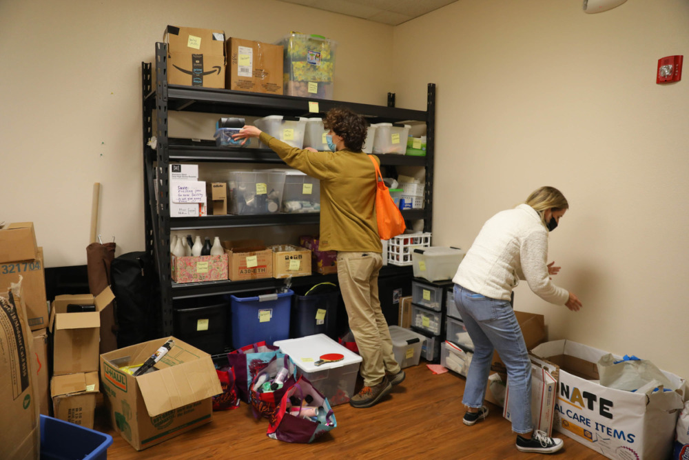 nonprofit homeless services: two adults sort through contents on shelves and boxes