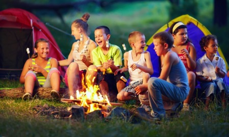 Alaska youth camp grants: group of happy children roasting marshmallows over fire