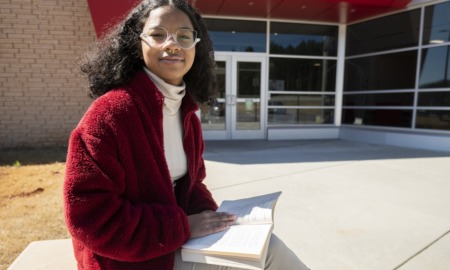 black girls see themselves in Supreme Court pick: young black girl with glasses reading a book in front of library entrance