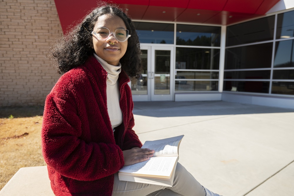 black girls see themselves in Supreme Court pick: young black girl with glasses reading a book in front of library entrance