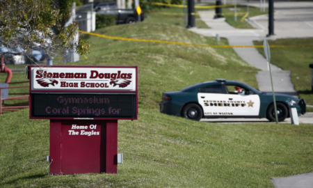 School triage training: Margory Stone Douglas High School sign on green lawn with police car in background
