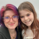 Tell kids about nuclear war: Headshot of white woman with pink-highlighted dark hair with red-framed glasses and young white girl with long, light brown hair smiling into camera.