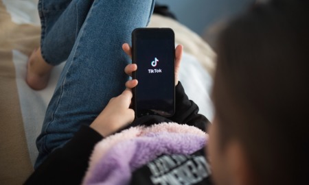 social media use, tiktok: young person laying down opening TikTok on phone