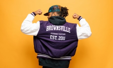 Brooklyn BIPOC community grants: Black youth on solid brightly colored background in jacket flexing arms