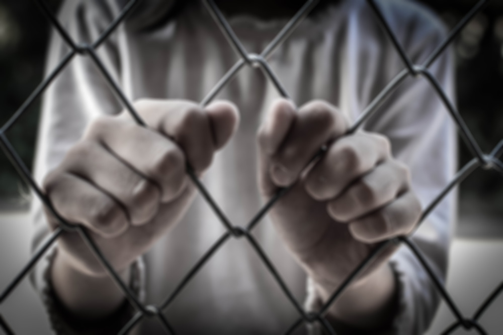 S.C. Juvenile Justice System lawsuit: Two hands intertwined with chain link fence close-up