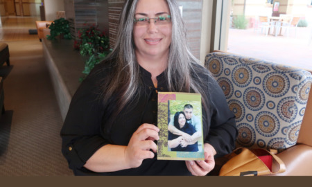 Juvenile lifers: Middle-aged woman with long dark, graying hair wearing black top stands holding collaged photo of her younger self with a young, dark-haired mn hugging her from the back