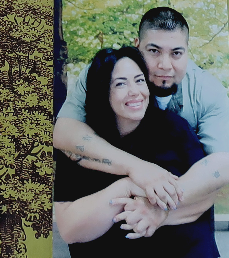 Juvenile lifers: Two dark-haired young adults stand together with man hugging woman from back with arms over her shoulders.