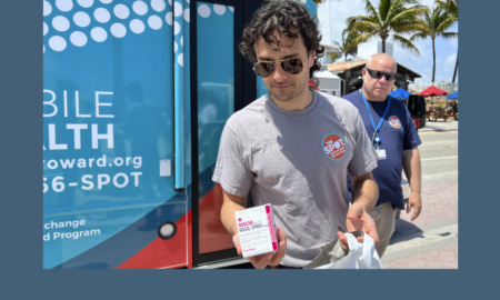 Youth drog overdoses: Young man wearing sunglasses stands with older amn in parking lot next to blue mobile medical vehicle