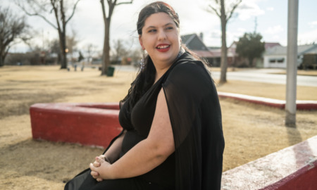 New Mexico foster care reform: woman with dark hair sitting on brick wall outside and smiling