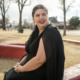 New Mexico foster care reform: woman with dark hair sitting on brick wall outside and smiling
