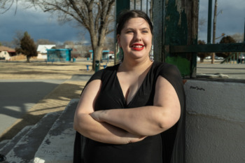 New Mexico foster care reform: woman with dark hair crossing arms and smiling while looking into the distance