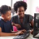 STEM education equity grants: Black female teacher helping a young black female student on computer