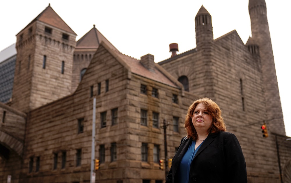 child neglect screening algorithm raises concerns: woman in dark blazer stands in front of large stone castle-inspired building
