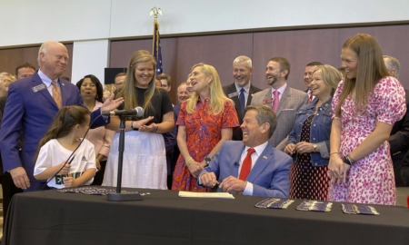 Georgia high school transgender athlete ban: group of people laughing at signing event