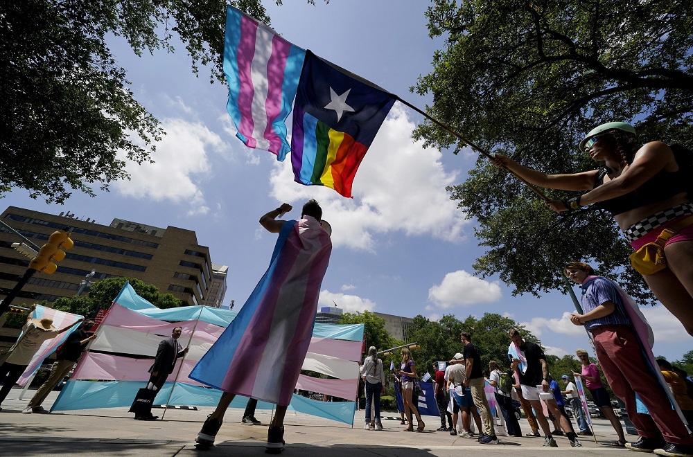 Texas ruling allows trans youth parent investigations: demonstrators gather with trans rights and LGBTQ flags on partly cloudy day