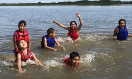 rural afterschool funding problems: group of children in lifevests playing in water