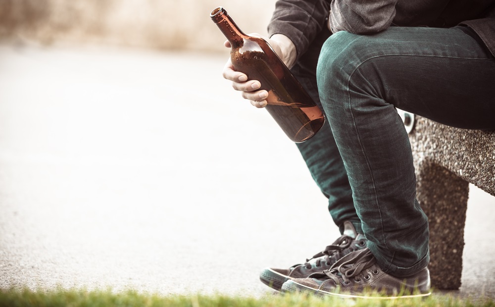 underage drinking prevention and reduction grants: youth sitting on bench drinking from bottle of wine