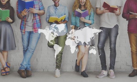 education internationalization grants: diverse happy students leaning against wall and reading with world map graphic overlaid