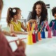 campus-based child care access grants: young woman works with children at table with lots of colored pencils