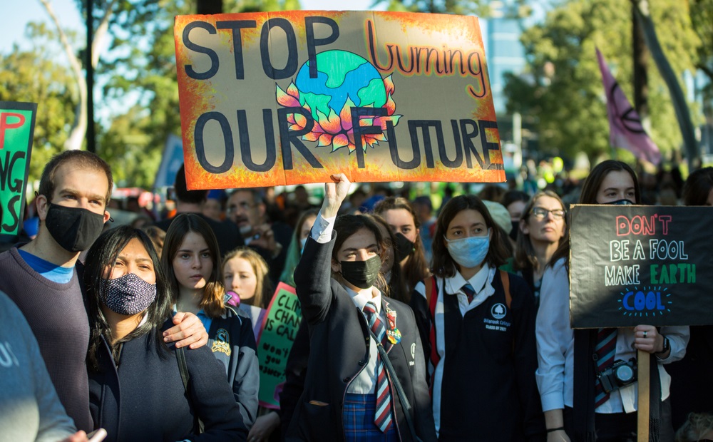 Climate change and youth mental health: image of youth protesting with sign that reads "stop burning our future"